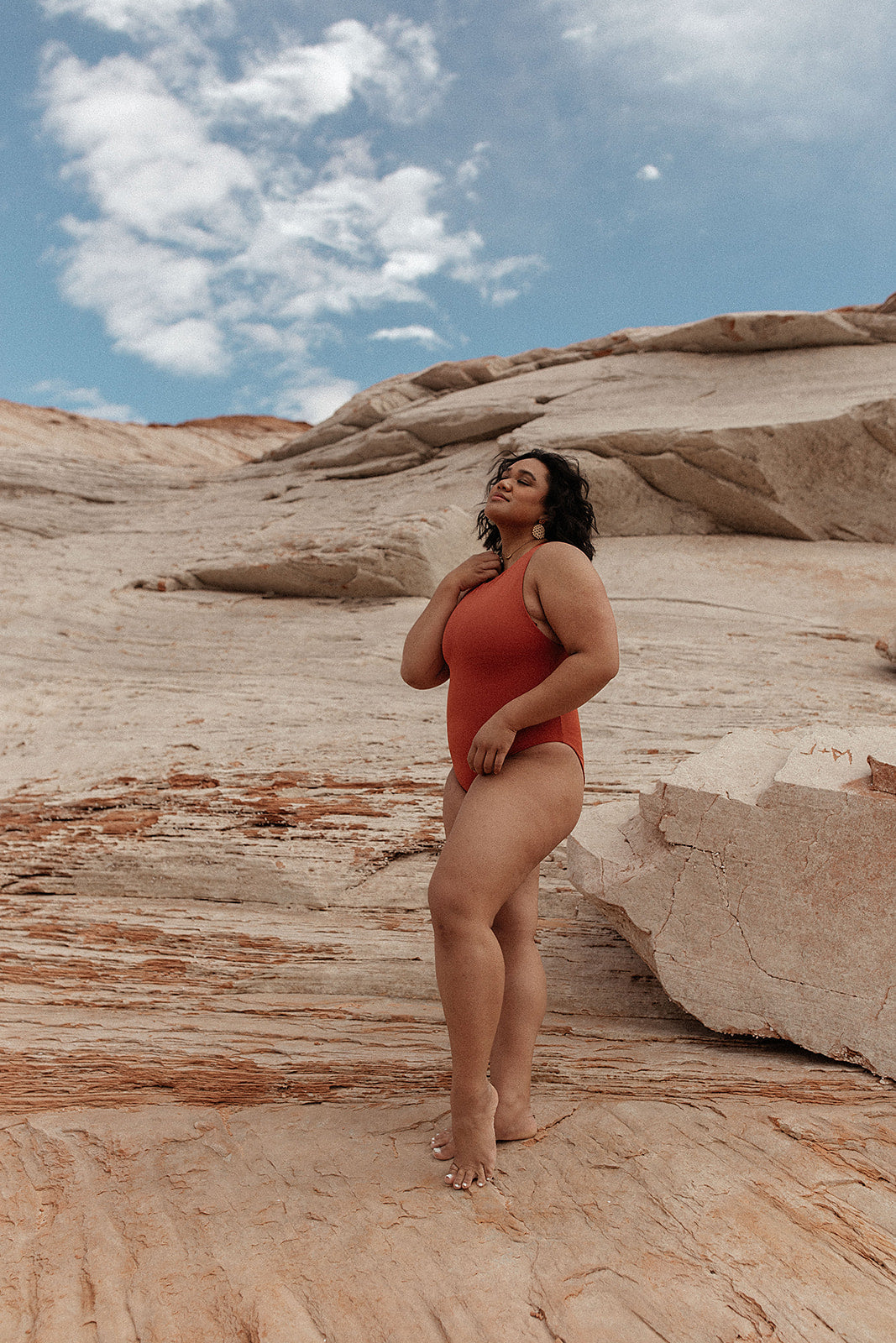 A red one-piece swimsuit featuring a modest high neckline, and medium coverage bottom. The suit has a back zipper closure and high-cut legs for a flattering fit.