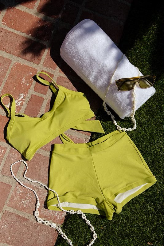 A flattering kiwi green bikini featuring a balconette style top with thick straps and a moderate scoop neck paired with midrise swim shorts offering full coverage in a bright, lively color.