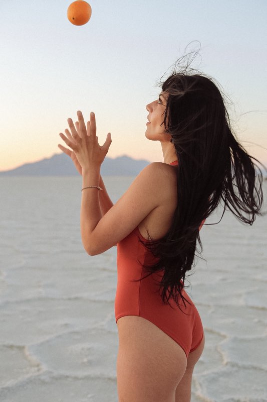 A red one-piece swimsuit featuring a modest high neckline, and medium coverage bottom. The suit has a back zipper closure and high-cut legs for a flattering fit.